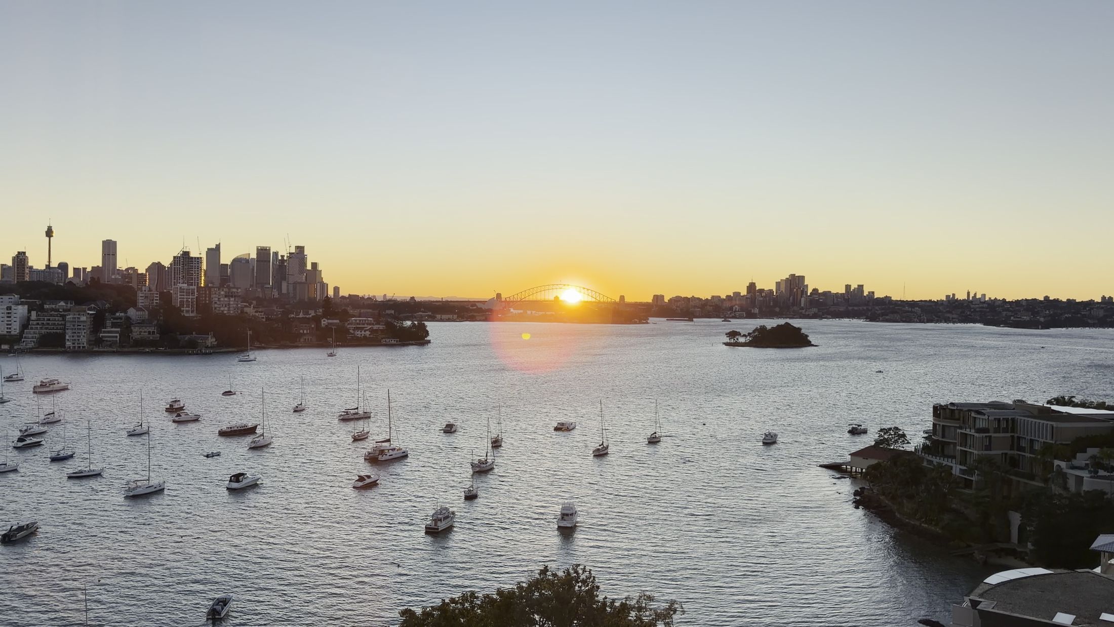 Sunset over the harbour from the Point Piper residence, boats moored and the city skyline beyond